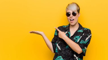 Genç kıvrımlı kadın bir yaz giyen palmiye bir kopya alanı tutarak heyecanlı bir görünüm.