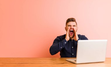 Dizüstü bilgisayarıyla çalışan genç adam öne doğru heyecanlanıyor.