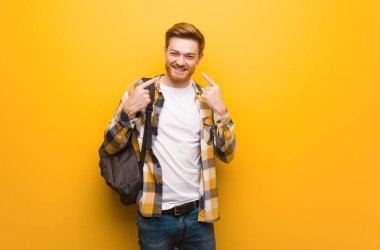 Genç kızıl saçlı öğrenci adam gülümsüyor, ağız işaret