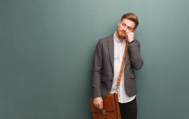 Genç kızıl saçlı iş adamı bir şey düşünüyor, yan bakıyor