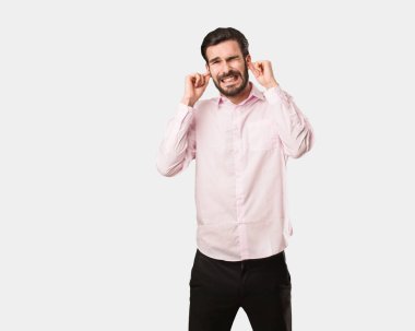 Genç yakışıklı adam elleriyle kulaklarını kapatıyor.