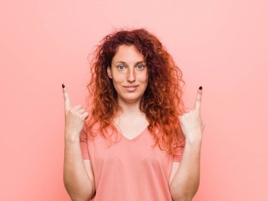 Genç doğal ve otantik kızıl saçlı kadın boş bir boşluk gösteren kadar her iki ön parmak ile gösterir.