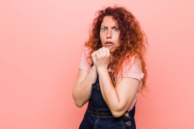Genç güzel kızıl kızıl kadın bir kot dungaree korkmuş ve korkmuş giyiyor.