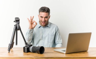 Genç yakışıklı fotoğrafçılık öğretmeni bir göz kırpıyor ve el ile tamam bir jest tutar.