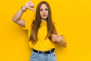 Genç kızıl kızıl saçlı kadın başparmak yukarı ve başparmak aşağı gösteren, zor kavramı seçin