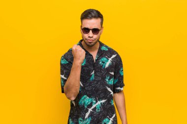 Genç filipinli adam kameraya yumruk gösteren yazlık giysiler giyen, agresif yüz ifadesi.