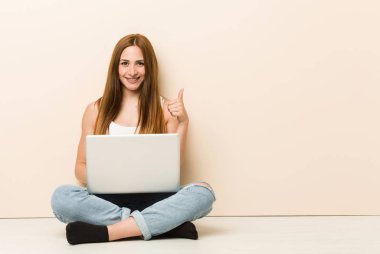 Genç zencefil kadın evinin katta gülümseyerek oturan ve başparmak yükselterek