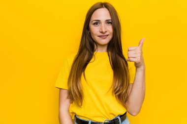 Genç kızıl kızıl saçlı kadın gülümseyerek ve başparmak yükselterek