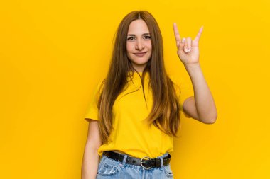 Genç kızıl kızıl saçlı kadın bir devrim kavramı olarak boynuzları jest gösteren.