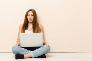 Evinin zemininde oturan genç zencefilli kadın omuz silkiyor ve gözleri karıştı.