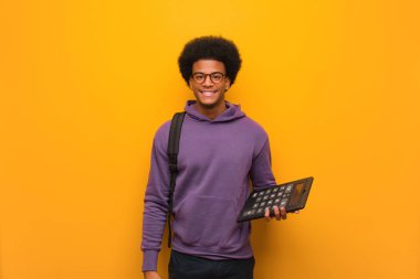 Genç afro-Amerikan öğrenci adam büyük bir gülümseme ile neşeli bir hesap makinesi tutan