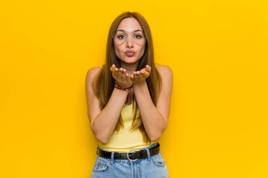 Huysuz katlanır dudakları ile genç kızıl saçlı zencefil kadın ve hava öpücük göndermek için avuç içi tutan.