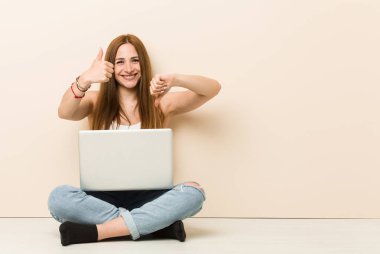 Genç zencefil kadın evinin zemin üzerinde başparmak yukarı ve başparmak aşağı gösteren oturan, zor kavramı seçin