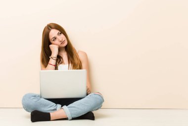 Genç zencefil kadın üzgün ve dalgın hissediyor evinin zeminüzerinde oturan, kopya alanı bakarak.