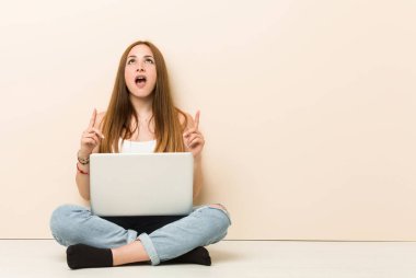 Genç zencefil kadın açık ağız ile ters işaret evinin zeminüzerinde oturan.