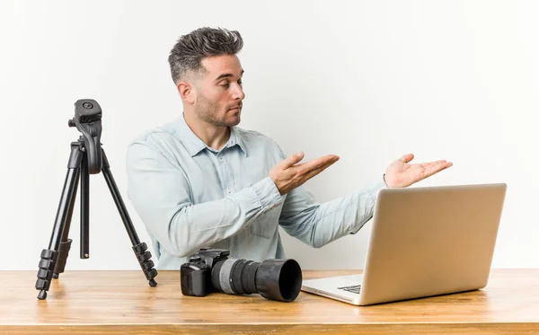 Young handsome photography teacher holding a copy space on a palm.