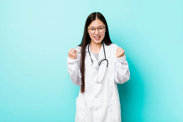 Young chinese doctor woman cheering carefree and excited. Victory concept.