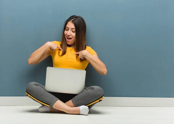 ノートパソコンを持って床に座っている若い女性は驚き 成功し 繁栄を感じる — ストック写真