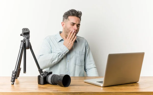 Young handsome photography teacher yawning showing a tired gesture covering mouth with hand.