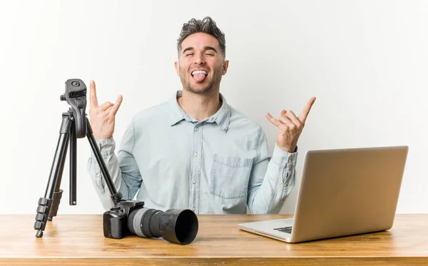 Young handsome photography teacher showing rock gesture with fingers