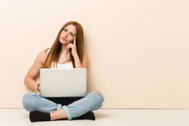 Genç zencefil kadın parmak ile tapınak işaret evinin zemininde oturan, düşünme, bir görev üzerinde duruldu.