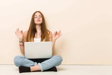 Evin katta oturan genç zencefilkadın zor iş gününden sonra rahatlar, o yoga yapıyor.