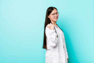 Genç Çinli doktor kadın işaret başparmak parmak uzakta, gülme ve kaygısız.