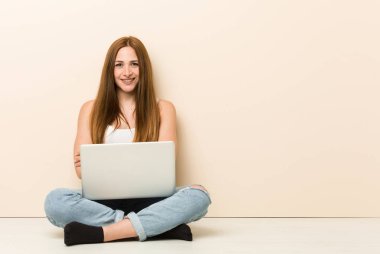 Genç zencefil kadın evinin zemininde gülerek ve eğleniyor oturuyor.