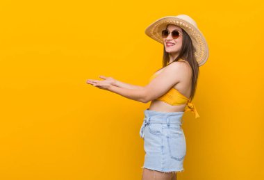 Hasır şapka takan genç beyaz kadın, bir avuç içinde bir kopya alanı tutan yaz bakmak.