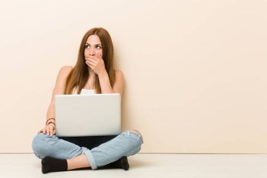 Genç zencefil kadın el ile ağız kapsayan bir kopyasını alan arıyor düşünceli evinin zeminüzerinde oturan.