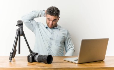Genç yakışıklı fotoğrafçılık öğretmeni başının arkasına dokunarak, düşünme ve bir seçim yapma.