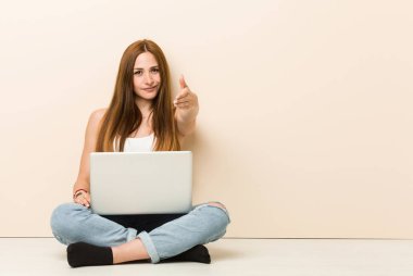 Genç zencefil kadın tebrik jesti kamera elini germe evinin zemininde oturan.