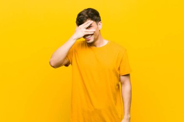 Genç İspanyol rahat adam parmakları ile kameraya göz kırpma, utanç yüzü kapsayan.