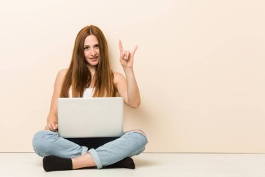 Genç zencefil kadın bir devrim kavramı olarak boynuzları jest gösteren evinin katta oturan.