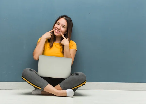 ノートパソコンの笑顔で床に座っている若い女性は 口を指差す — ストック写真