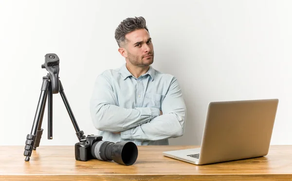 Young handsome photography teacher who feels confident, crossing arms with determination.