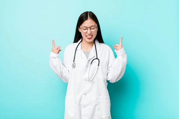Young chinese doctor woman showing rock gesture with fingers
