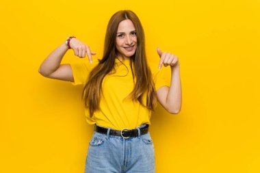 Genç kızıl kızıl saçlı kadın parmakları ile aşağı işaret, olumlu duygu.