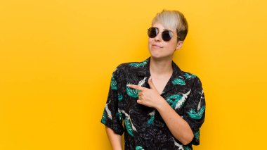 Genç kıvrımlı kadın bir yaz görünüm gülümseyen ve bir kenara işaret giyen, boş alanda bir şey gösteren.