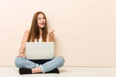 Genç zencefil kadın başparmak parmak uzakta, gülerek ve kaygısız ile evinin zemin noktaları üzerinde oturan.