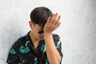 Yaz kıyafeti giyen genç Çinli adam unutkan, bir şey fark