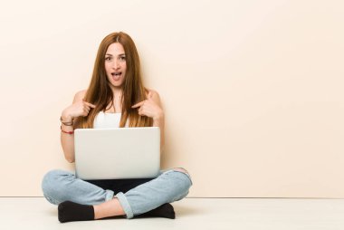 Evinin zemininde oturan genç zencefilli kadın, geniş gülümseyerek, parmakla işaret şaşırttı.