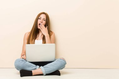 Genç zencefil kadın el ile ağız kapsayan yorgun bir jest gösteren evin indene otururken.