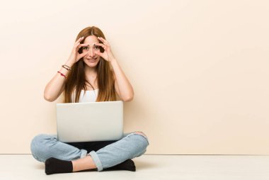 Genç zencefil kadın bir başarı fırsatı bulmak için gözleri açık tutarak evinin zeminüzerinde oturan.