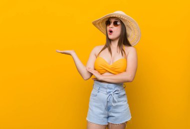 Hasır şapka takan genç beyaz kadın, yaz görünümünde avuç içi üzerinde kopya alanı tutarak etkilendi.