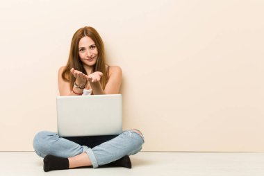 Genç zencefil kadın avuç içi ile bir şey tutarak, kamera sunan evinin zemininde oturan.