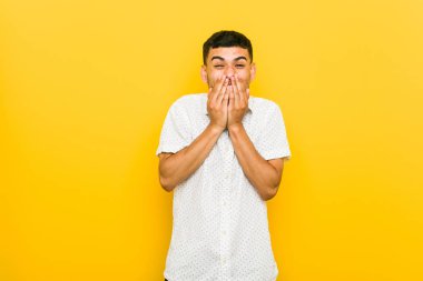 Genç İspanyol adam bir şey hakkında gülüyor, elleriyle ağız kapsayan.