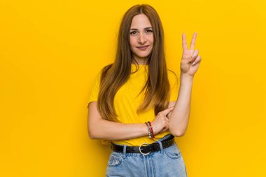 Genç kızıl kızıl saçlı kadın parmakları ile iki numara gösteren.