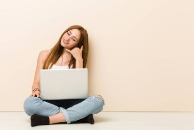 Genç zencefil kadın parmakları ile bir cep telefonu arama jestgösteren evinin katta oturan.