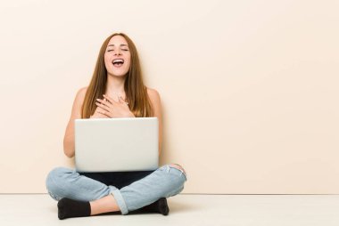 Evin inkatında oturan genç zencefilli kadın gülerek kalp, mutluluk kavramı ellerini tutarak.